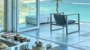 A modern room with a glass door leading to a balcony overlooking a beach and ocean. - Stunning mansion in Joatinga, Rio de Janeiro. (Rio de Janeiro)