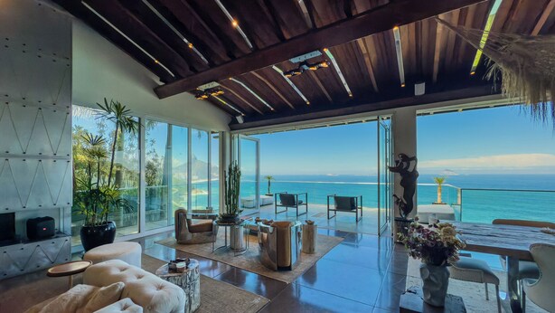A spacious living area with a large window overlooking the ocean, furnished with modern seating and a dining table. - Stunning mansion in Joatinga, Rio de Janeiro. (Rio de Janeiro)