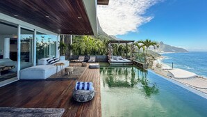 A modern outdoor living area with a wooden deck, a pool, and a view of the ocean. - Stunning mansion in Joatinga, Rio de Janeiro. (Rio de Janeiro)