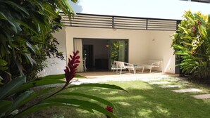 A modern building with a flat roof and large windows. There is a patio area with white chairs and a table. - 2 Bedroom Pool Apartment (Las Terrenas)