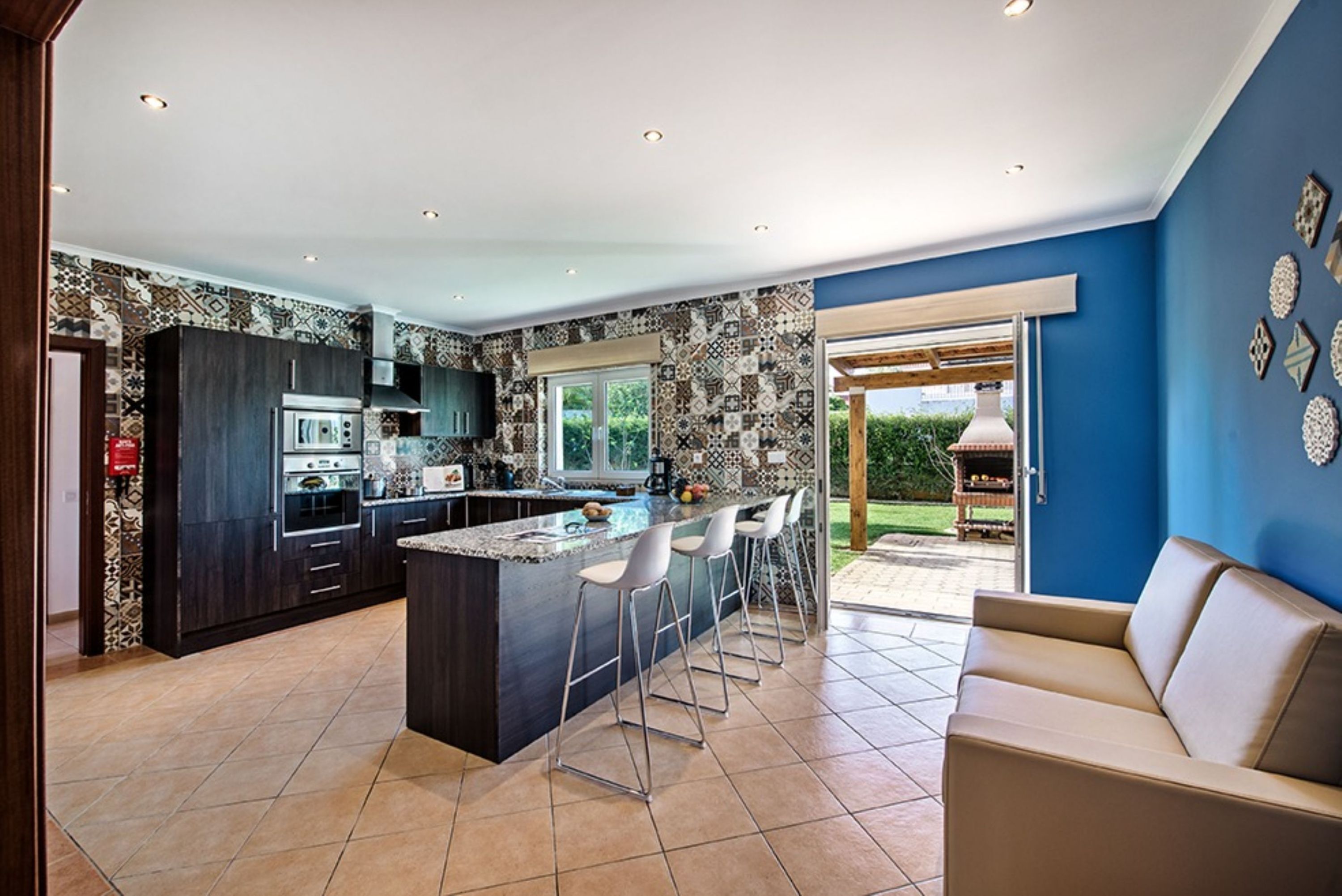 A modern kitchen with dark cabinetry, a central island with bar stools, and a large window.