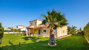 A two-story house with a well-maintained lawn and a palm tree in the front yard. - Amapola in Quelfes with 4 bedrooms and 4 bathrooms (Quelfes)