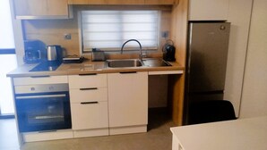 A compact kitchen with wooden cabinets, a built-in oven, a sink, and a refrigerator.