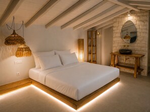 Une chambre à coucher avec un lit, une table de chevet en bois, un miroir fixé au mur et un luminaire suspendu.