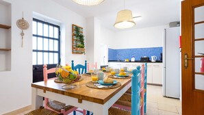 Un coin repas avec une table en bois, des chaises en osier et une table dressée pour le petit-déjeuner.