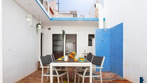 Une terrasse avec une table dressée pour deux personnes, un mur recouvert de carreaux bleus et un plafond blanc.