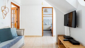 Un salon moderne avec un canapé, une table en bois sur laquelle sont posés des appareils électroniques, et un téléviseur fixé au mur.