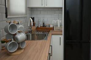 A kitchen with a wooden countertop, stainless steel sink, and white cabinets. - Nueva Lycabettus by Neuvel  · (Athina)