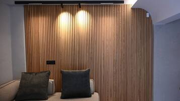 Una stanza con parete in listelli di legno, un divano con due cuscini e un lampadario.