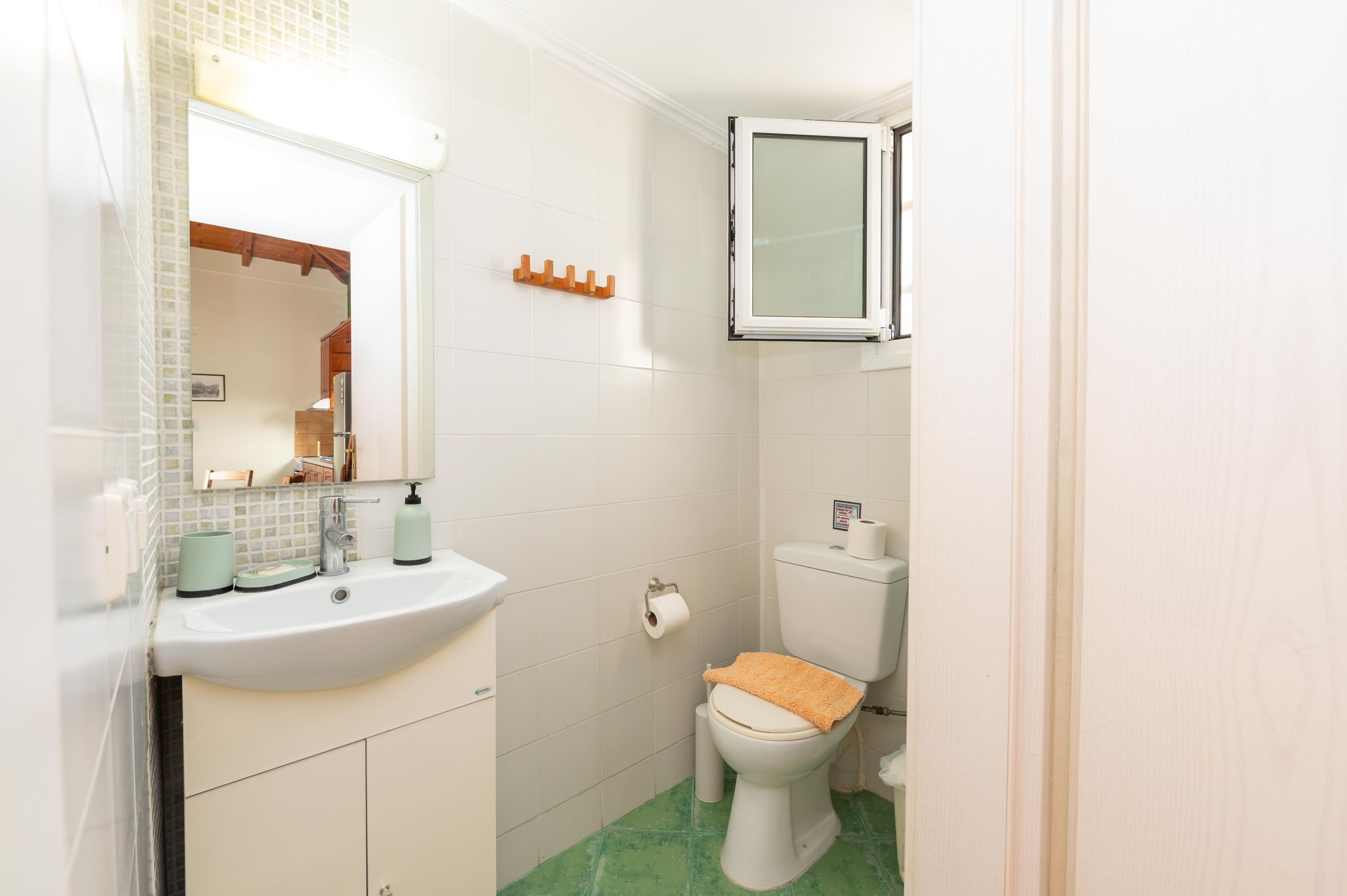 A bathroom with a white sink, mirror, toilet, and a cabinet.