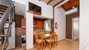 A compact kitchen with a dining table, wooden cabinets, a small oven, and a staircase. - Τριαντάφυλλο/Rose near to sea with heating pool (Mavrovouni)