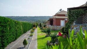 A pathway leading to a house with a stone facade and a red door. - Τριαντάφυλλο/Rose near to sea with heating pool (Mavrovouni)
