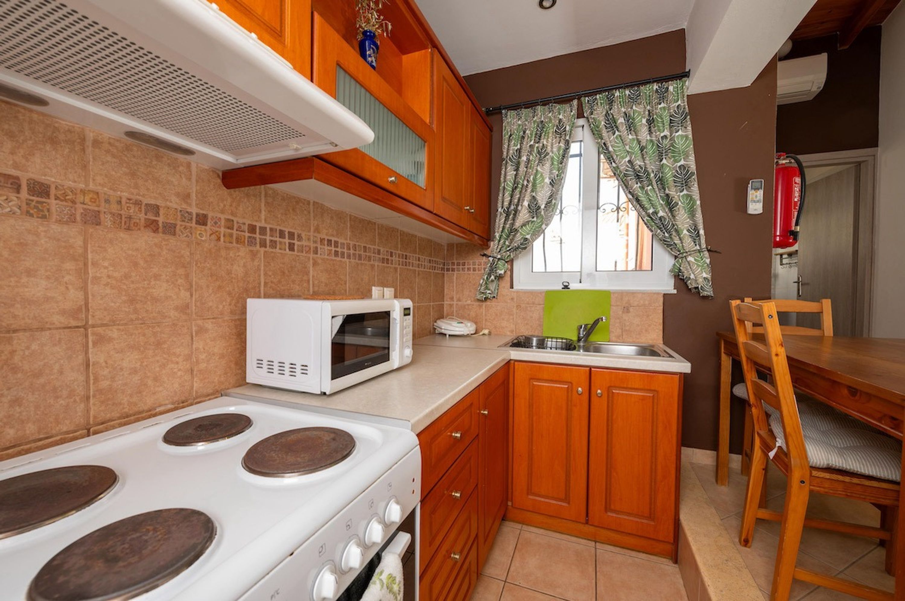 Eine kleine Küche mit Herd, Mikrowelle und Holzschränken.
