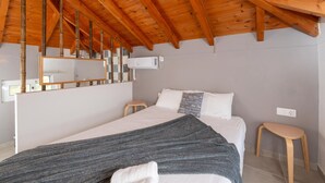 A bedroom with a wooden ceiling, a bed with white bedding, a gray blanket, a bedside table, and a mirror. - Τριαντάφυλλο/Rose near to sea with heating pool (Mavrovouni)