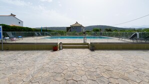 Piscina com um pátio de pedra em primeiro plano e vista para colinas ao fundo.