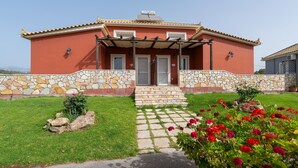 Um edifício vermelho com fachada de pedra, telhado telhado e um pequeno jardim com flores vermelhas.