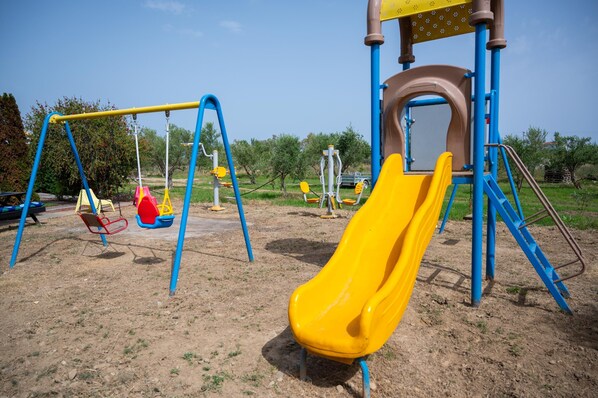 Une aire de jeux avec des balançoires, un toboggan et des structures d’escalade.