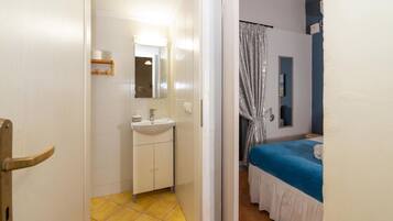 A bathroom with a sink, mirror, and yellow-tiled floor.