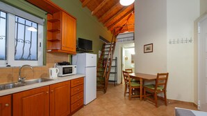 Une cuisine compacte dotée de meubles en bois, d’un four à micro-ondes, d’un réfrigérateur, d’un évier et d’un coin repas avec une table et des chaises.