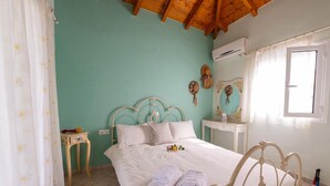 Une chambre à coucher avec un lit, une petite table de chevet, un miroir et une fenêtre avec des rideaux.