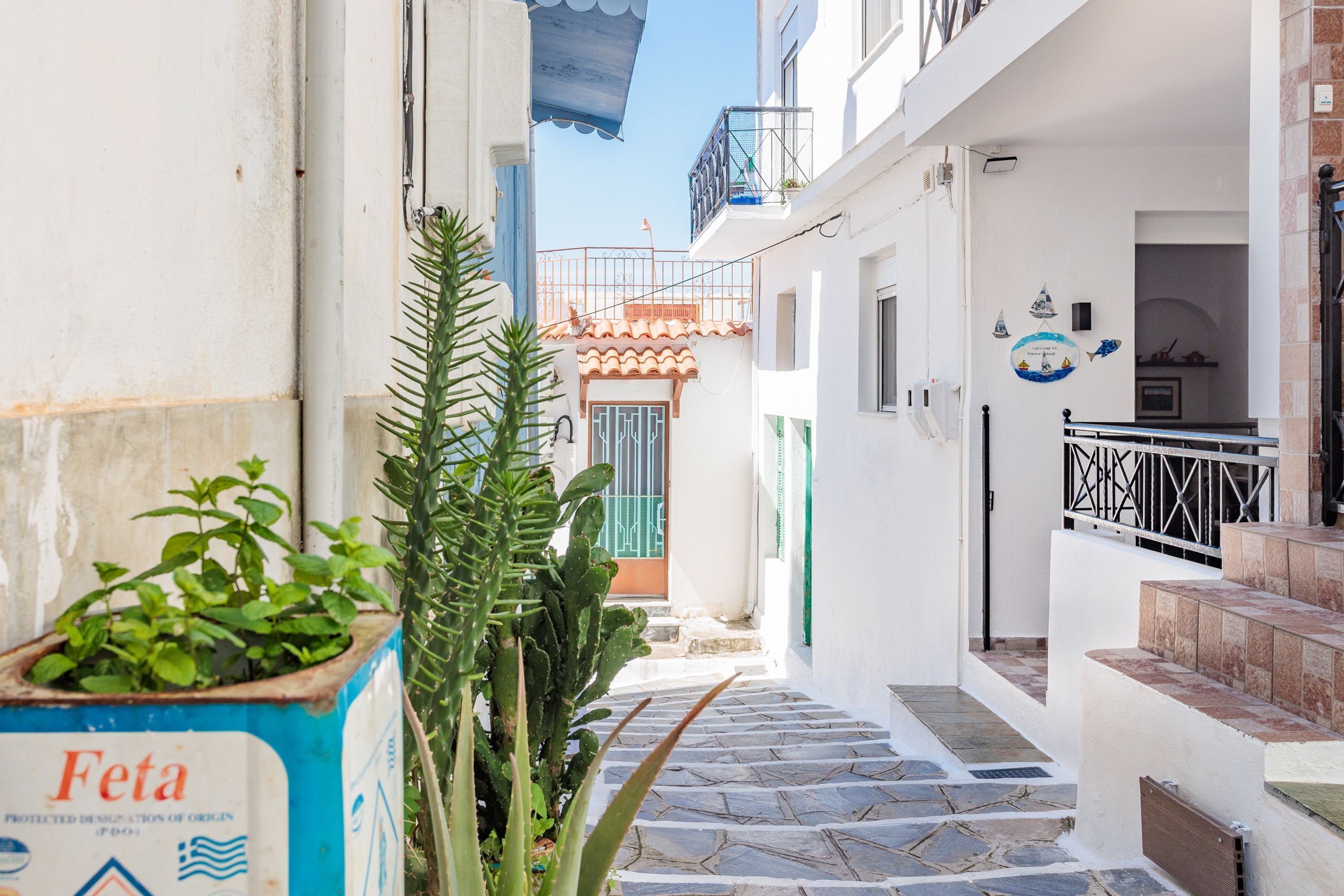 A narrow alleyway with a staircase leading to a building with a tiled roof and a balcony.