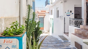 Une ruelle étroite avec un escalier menant à un immeuble doté d’un toit en tuiles et d’un balcon.