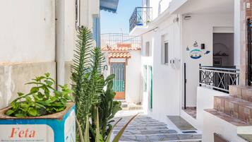 A narrow alleyway with a staircase leading to a building with a tiled roof and a balcony.