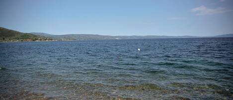 A clear view of a lake with a shoreline and distant hills.