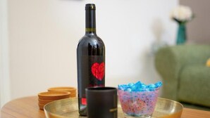 A bottle of wine, a black mug, and a colorful glass on a tray. - Crown Syntagma Apartment (Athina)