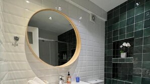A modern bathroom with a white vanity, a round mirror, and a toilet. - Crown Syntagma Apartment (Athina)