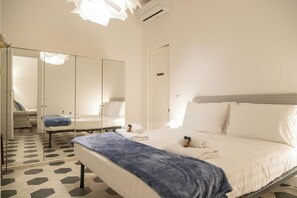 Una camera d'albergo con un letto, uno specchio, un armadio e una zona salotto.