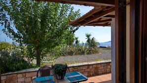 A patio with a table and chairs, a potted plant, and a view of the landscape. - Kamelia Villa 1 in Alonissos (Votsi)