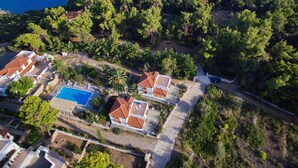 An aerial view of a coastal property with a swimming pool, terraced houses, and dense greenery. - Kamelia Villa 1 in Alonissos (Votsi)