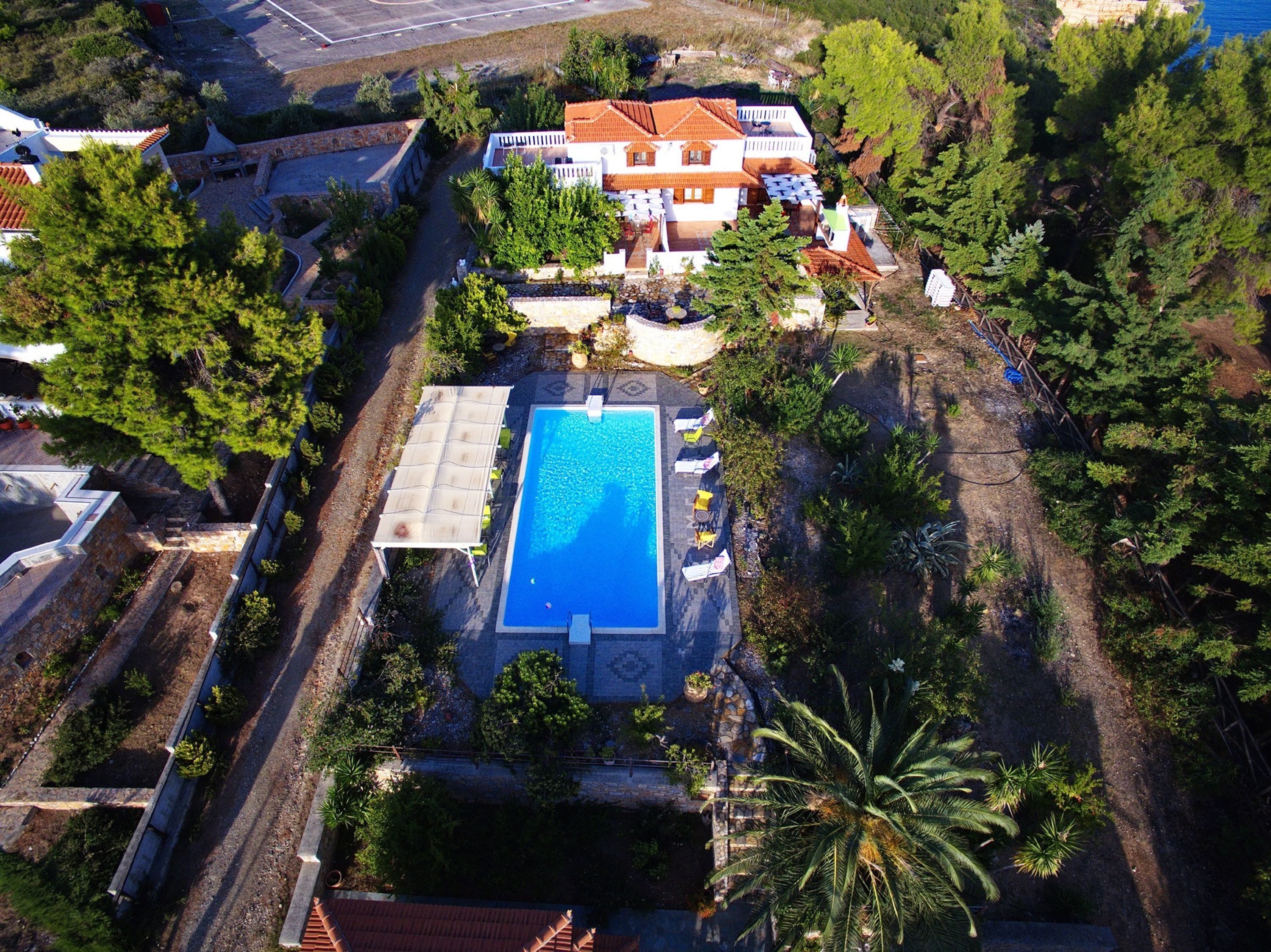 An aerial view of a property with a swimming pool, a covered patio, and a garden area.