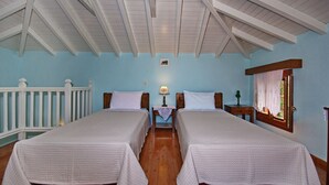 Quarto com duas camas, teto de madeira, janela com cortinas de renda e uma mesa pequena com abajur.