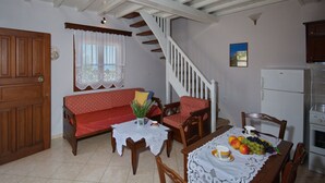 A cozy kitchen with a dining area, wooden furniture, a staircase, and a refrigerator. - Kamelia Villa 3 in Alonissos (Votsi)