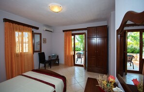 Ein Hotelzimmer mit Bett, Schreibtisch mit Fernseher, Kleiderschrank und Blick auf den Außenbereich.