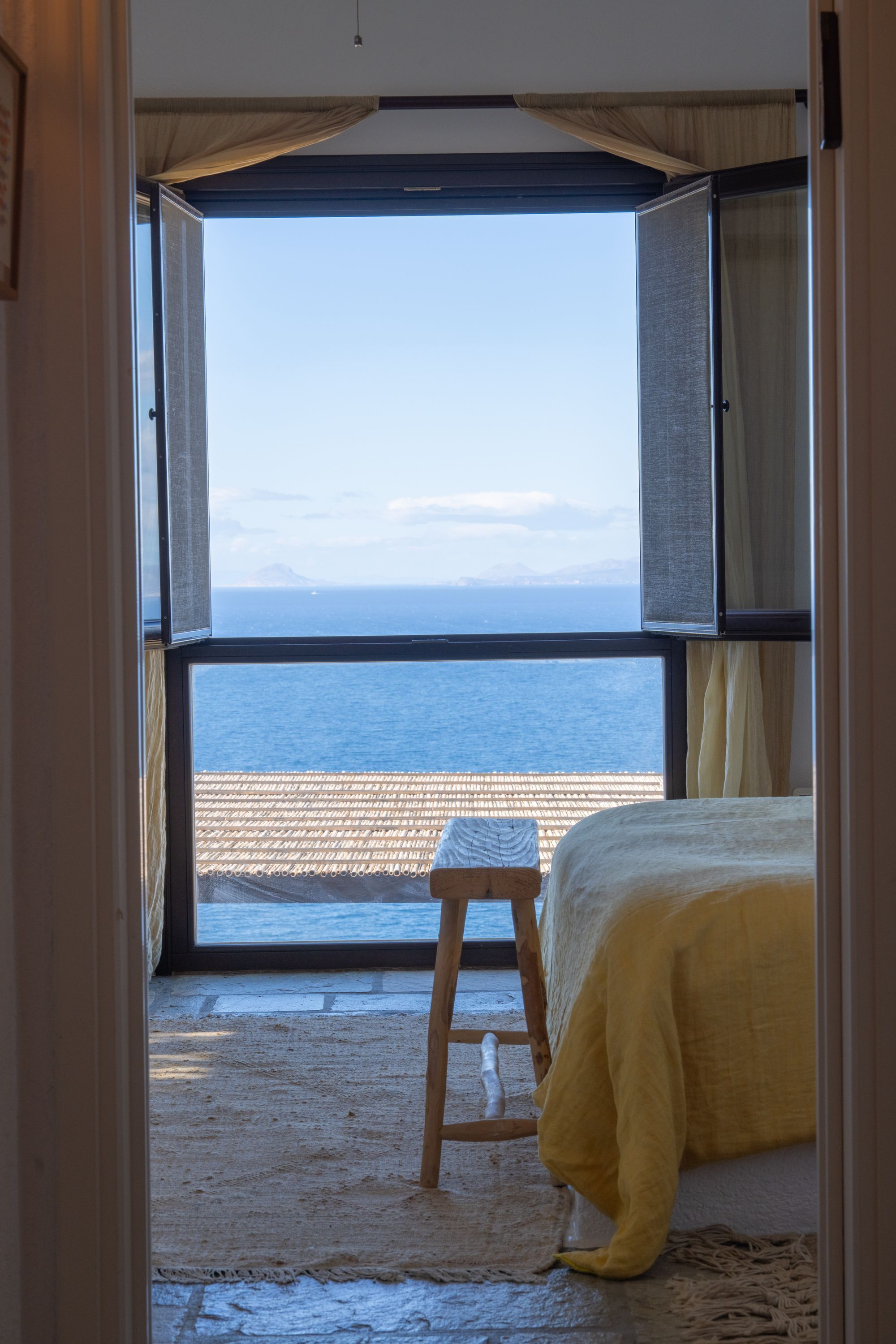 Un dormitorio con un ventanal grande con vista a la playa.