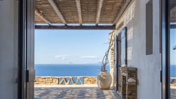 Une porte ouverte donne sur un patio dallé de pierres, d’où l’on peut admirer la mer.
