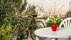 A bicycle parked next to a white table with a red vase of flowers. - Villa del Cortile Ionico (Porto Cesareo)