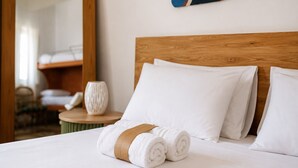 A neatly made bed with white linens, a wooden headboard, and a rolled towel with a brown band. - Villa del Cortile Ionico (Porto Cesareo)