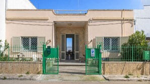 A building with a gated entrance, a small balcony, and a clear sky. - Villa del Cortile Ionico (Porto Cesareo)