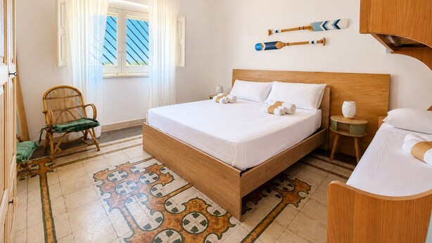 A hotel room with a bed, a chair, a small table, and a window with curtains. - Villa del Cortile Ionico (Porto Cesareo)