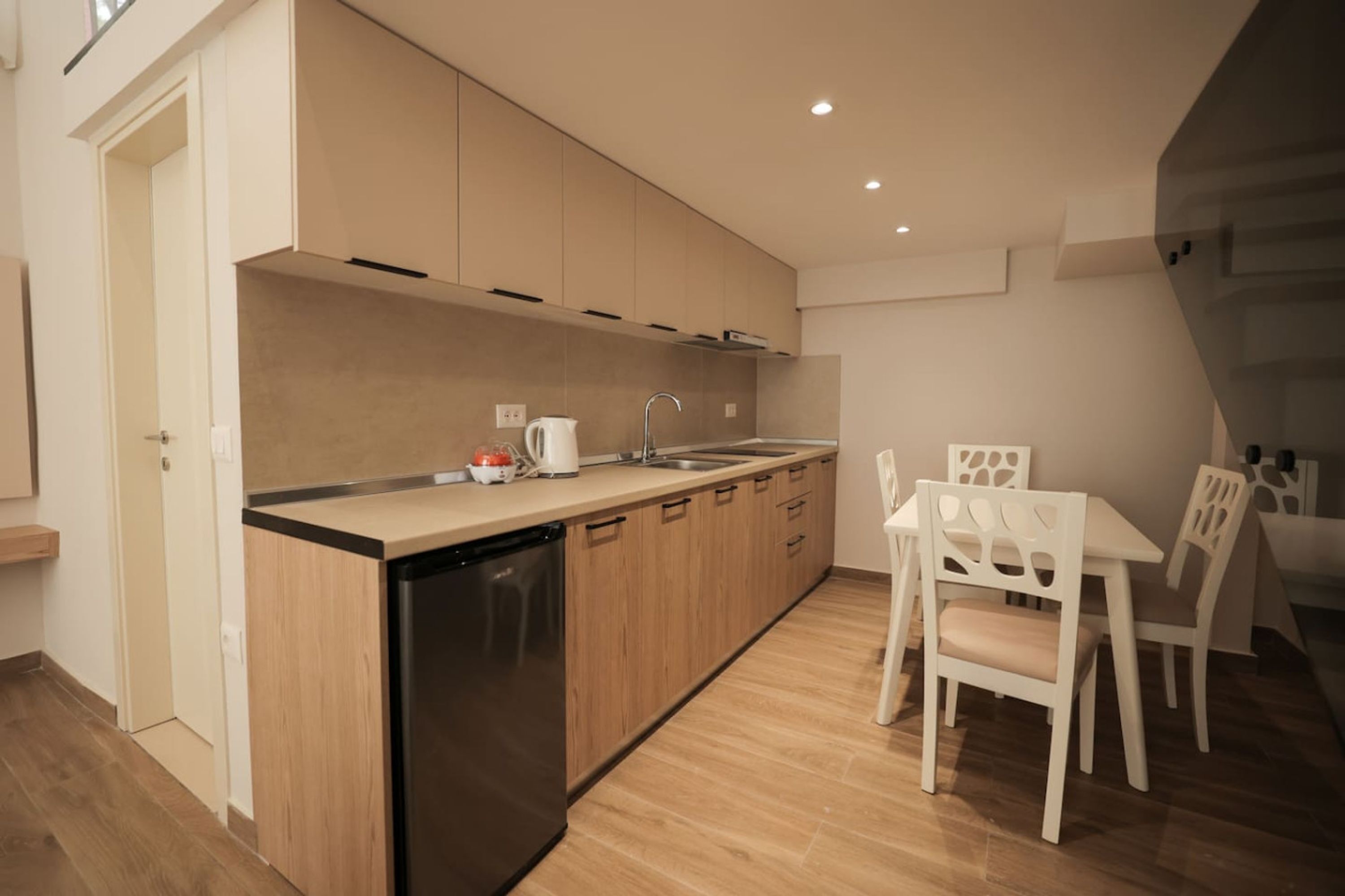 Eine moderne Küche mit Holzausstattung, einem Geschirrspüler sowie einem Essbereich mit weißen Stühlen und einem Tisch.