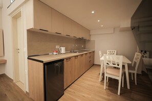 A modern kitchen with wooden cabinets, a dishwasher, and a dining area with white chairs and a table. - Duplex City 08 in Durrës (Durrës)