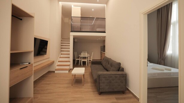 A modern apartment with a loft bedroom, a dining area, and a living room with a sofa and a TV. - Duplex City 05 in Durrës (Durrës)