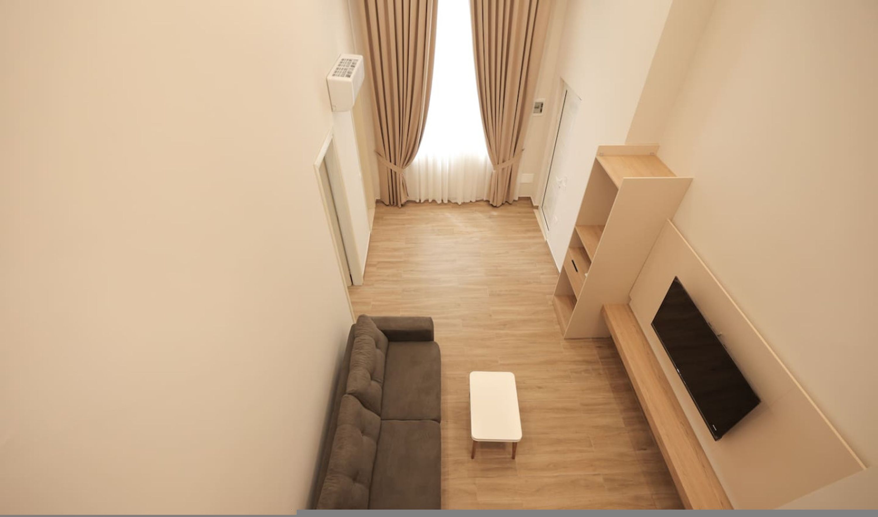 A modern living room with a sofa, a coffee table, and a TV mounted on the wall.