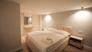 Ein ordentlich bezogenes Bett mit Kopfteil, Nachttisch und Beistelltisch.