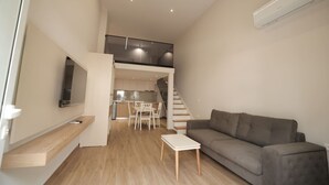 Eine moderne Wohnung mit Wohnzimmer, Essbereich und Küche. Eine Treppe führt zu einer oberen Ebene.