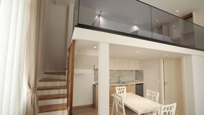Eine moderne Wohnung mit Essbereich, Küche und einer Treppe, die zu einem Schlafzimmer auf dem Dachboden führt.